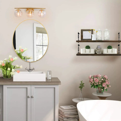 Bathroom with three light gold vanity light fixture with clear globe glass shades and slim taper arm above round mirror
