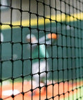 Close-up of Heavy Duty Batting Cage Netting, Fully Enclosed Baseball And Softball Cage Net, Weatherproof HDPP Twine, player in background.