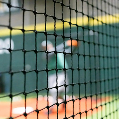 Close-up of Heavy Duty Batting Cage Netting, Fully Enclosed Baseball And Softball Cage Net, Weatherproof HDPP Twine, player in background.
