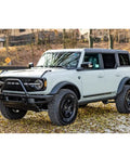 Ford Bronco SUV parked in forest setting, showcasing rugged design and off-road capability with focus on front grill and tires