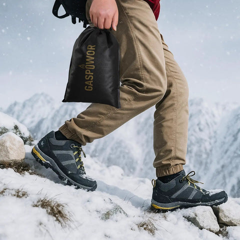 Person walking on snowy mountain with hiking boots and holding a black bag labeled 'GASPOWER'