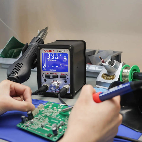 Hands using the 2 In 1 Hot Air Rework And Soldering Iron Station with LCD screen and PID control for soldering a circuit board.