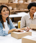 Two women packing Rock Solid 50 Pack Small Shipping Boxes 6x6x2 Inch Brown Kraft Corrugated Cardboard Mailing Cartons.