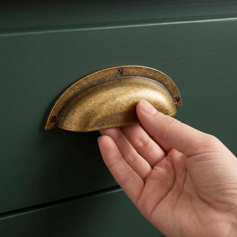Transform Your Kitchen Setup With 3 Inch Antique Brass Cup Pulls Heavy Duty Solid Zinc Alloy Drawer Handles Vintage Home Office Cabinet Knobs 6 Pack. Hand grasping a vintage brass cup pull on green drawer.
