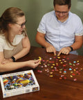 Two people assembling the Hot Air Balloon Festival 1000 Piece Jigsaw Puzzle With Easy Grip Pieces on a table.