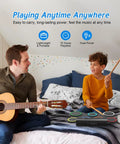 Child playing Roll Up 7 Pad Electronic Drum Set Midi Drum Kit with headphones while man plays guitar on bed.