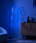 Dope RGB Color Changing Floor Lamp With Arching Three-Ring Pendant in modern living room, dimmable LED, black sleek finish, ambient blue glow.