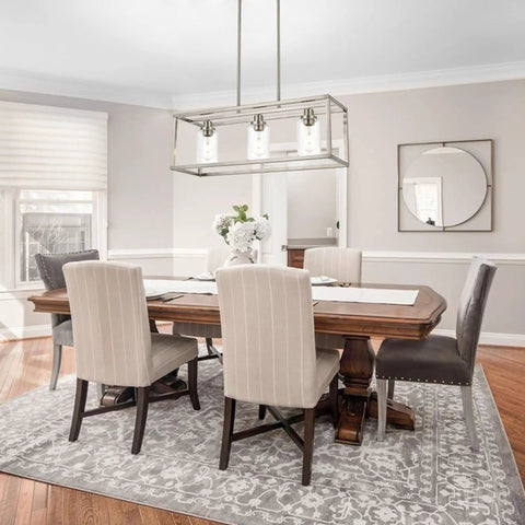 Rectangle Chandelier With 3 Lights In Brushed Nickel Finish hanging over a dining table with clear glass shades.