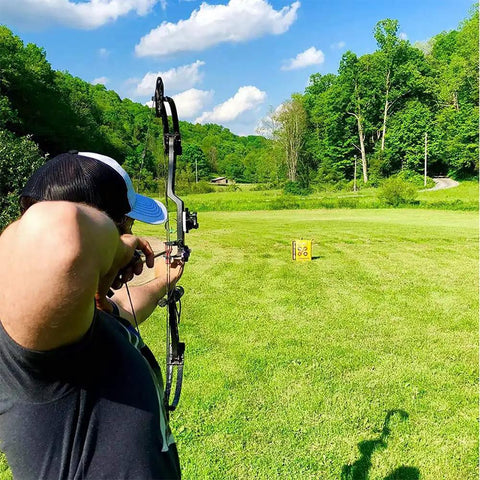 Archer aiming at Yellow Jacket Stinger Field Point Archery Target Bag with Dual Sides and Ten Bullseyes in a green field