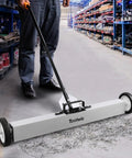 Heavy Duty 36 Inch Rolling Magnetic Sweeper With Quick Release Handle cleaning up metal debris from a garage floor.