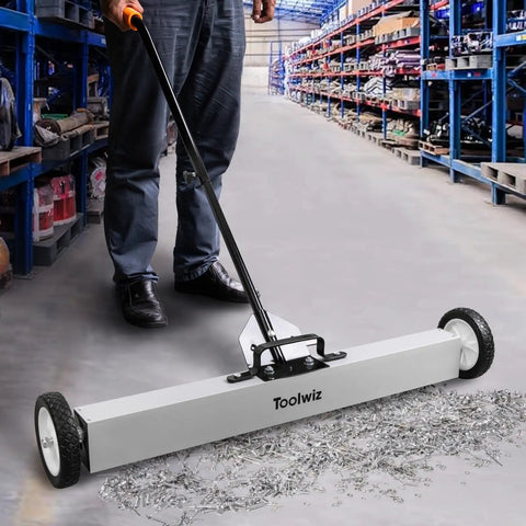 Heavy Duty 36 Inch Rolling Magnetic Sweeper With Quick Release Handle cleaning up metal debris from a garage floor.