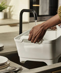Person using Wash And Drain Kitchen Dish Tub with Handles and Twist Drain Plug 9 Liter Basin under a faucet in kitchen.