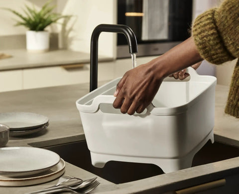 Person using Wash And Drain Kitchen Dish Tub with Handles and Twist Drain Plug 9 Liter Basin under a faucet in kitchen.