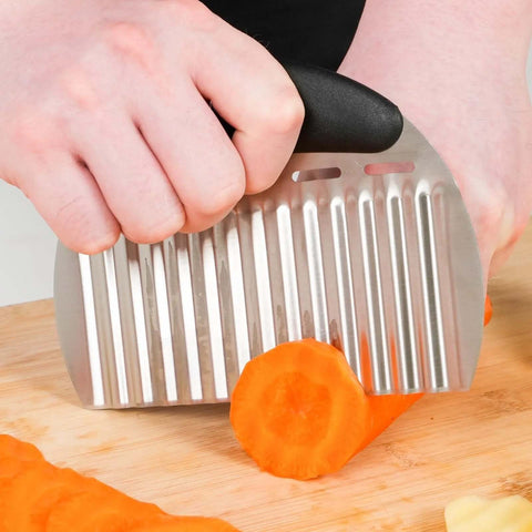 Close-up of a heavy-duty stainless steel crinkle cutter with an ergonomic black handle slicing a carrot.