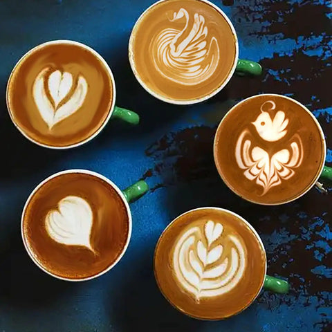 Top view of five cups with latte art designs, showcasing creativity in foam made with Stainless Steel Milk Frothing Pitcher 12 Oz 350ml.