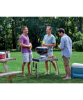 Three men enjoying outdoor gathering with Jumbo Joe Charcoal Grill 18 Inch Portable Kettle Bbq on a summer day.