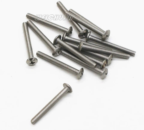 Pile of metallic screws with flat heads scattered on a white surface