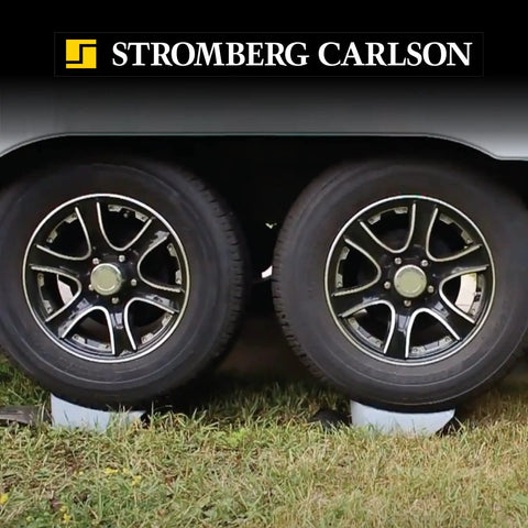 Base Pad Leveler Wheel Chock Set For RV And Trailer Leveling Blocks in use beneath trailer wheels for stability.