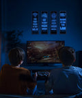 Two boys playing video games with Glow In The Dark Gamer Wall Decals Four Piece Set Featuring Joystick Controller Stickers above TV screen.