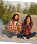 Two campers enjoying drinks near a tent, showcasing 8 Piece Portable Stainless Steel Camping Cookware Set With Fire Resistant Pots And Bowls.