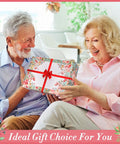 Elderly couple exchanging a floral gift box labeled '11 Piece Floral Garden Tool Set With Non Slip Handles Heavy Duty Hand Tools Kit Includes Tote Gloves Knee Pad Sprayer And Towel Sweet Gift For Women Moms Birthday'