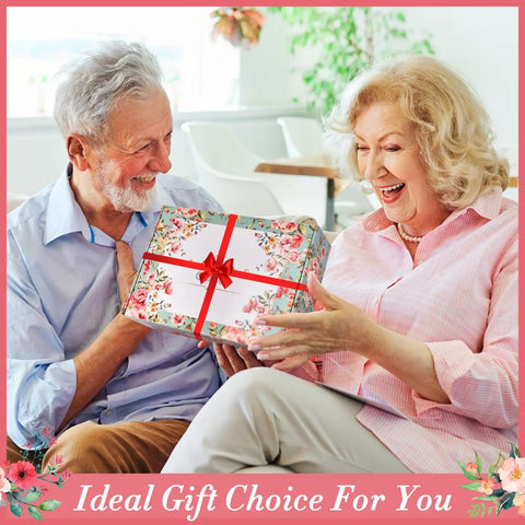Elderly couple exchanging a floral gift box labeled '11 Piece Floral Garden Tool Set With Non Slip Handles Heavy Duty Hand Tools Kit Includes Tote Gloves Knee Pad Sprayer And Towel Sweet Gift For Women Moms Birthday'
