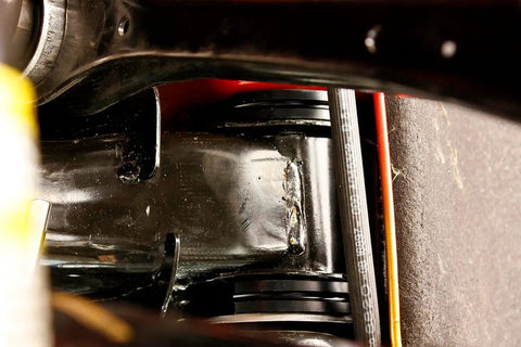 Close-up view of Delrin Rear Cradle Bushing Kit Boasting Zinc Coated Sleeves installed in chassis for enhanced handling.