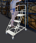 Rock Solid Four Step Rolling Ladder With Sturdy Rails And Non Slip Steel Treads Built Tough For No Fuss Warehouse Access. Man climbing ladder.