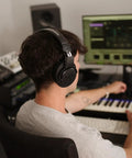 Person wearing M20x Professional Studio Headphones for Mixing and Monitoring, lightweight circumaural over ear design in home studio.