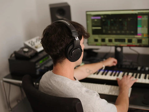 Person wearing M20x Professional Studio Headphones for Mixing and Monitoring, lightweight circumaural over ear design in home studio.