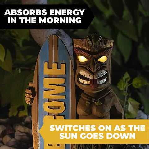 Welcome Tiki Statue With Surfboard Solar Powered 14 Inch Outdoor LED Light Decor with glowing eyes at night in garden.