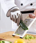 Chainmail Glove Cut Resistant Food Grade Stainless Steel Mesh Safety Glove For Butchers Oyster Shucking Mandoline Slicing Fish Fillet Medium Size Ultra Flexible 304 Stainless Rings For Superior Hand Protection being used for slicing cucumber on a mandoline.