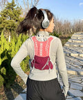 Person wearing a pink Lightweight Running Vest Hydration Backpack with Breathable Mesh Back on a sunny trail.