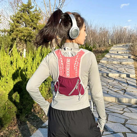 Person wearing a pink Lightweight Running Vest Hydration Backpack with Breathable Mesh Back on a sunny trail.