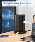Black Ultimate Surge Protector Power Strip Tower with 16 outlets, 4 USB ports, and 15 ft extension cord on a desk by a window.