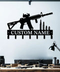 Custom Name Gun Themed Wall Hooks For Keys And Coats in black metal, shaped like a rifle with bullet accents, wall mounted above a desk.