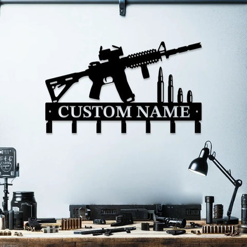 Custom Name Gun Themed Wall Hooks For Keys And Coats in black metal, shaped like a rifle with bullet accents, wall mounted above a desk.