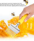 Stainless Steel Honeycomb Uncapping Fork For Beekeeping held in hand over honeycomb, visible yellow handle and steel tines.