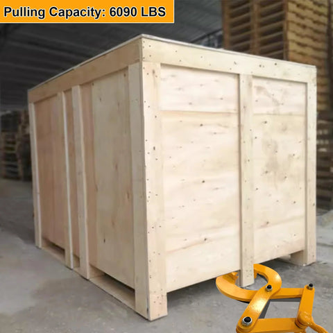 Pallet puller clamp, orange steel, in front of a large wooden shipping crate.