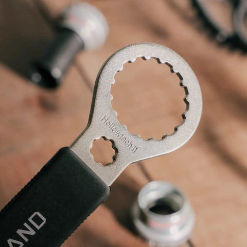 Close-up of Hollowtech II double-ended bottom bracket tool with 16 notches on wooden surface.