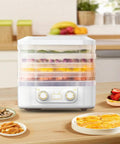 Big League Food Dehydrator Machine With Six Stackable Trays, white countertop model visible with dried snacks around it.
