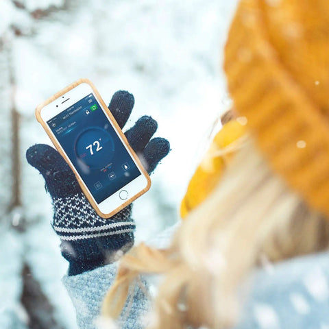 Person using Wi Fi Connected Thermostat With Alexa And Google Assistant All In One Touch Screen Controller on phone in snowy setting