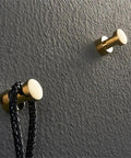 Top Tier Pack Of Four Heavy Duty Stainless Steel Wall Hooks With Rust Proof Finish For Bathrooms And Kitchens Showcasing Sleek Modern Lines To Hang Coats Towels And Keys Smooth As Butter In The Morning on a textured wall with a black braided rope.