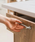 Hand holding silver twig branch handle from 10 Pack Zinc Alloy Twig Branch Cabinet Knob Set In Silver Decorative Pull Handles For Cabinets Dressers Wardrobes Drawers And Furniture Doors Durable Hardware With Easy Install And Strong Grip.
