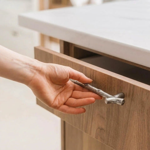 Hand holding silver twig branch handle from 10 Pack Zinc Alloy Twig Branch Cabinet Knob Set In Silver Decorative Pull Handles For Cabinets Dressers Wardrobes Drawers And Furniture Doors Durable Hardware With Easy Install And Strong Grip.