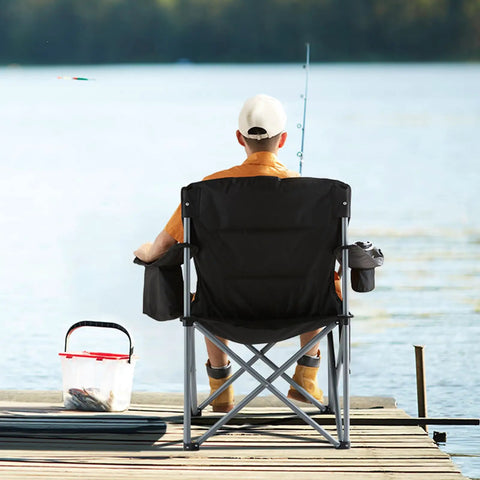 Man fishing on dock with Oversized Camping Folding Chair With Quad Lumbar Back Support, cup holder, and cooler bag