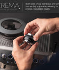 Hands holding 53.3mm Coffee Distributor And Hand Tamper For Breville Portafilters with adjustable depth over espresso machine.