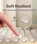 Person pressing a clear silicone cabinet door bumper, 256 Piece Bulk Pack Clear Silicone Cabinet Door Bumpers Sticks Like Glue Half Inch Rubber Furniture Protectors Soft Close Pads To Keep Your Cabinets Chill And Quiet During Everyday Use.
