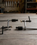 Two Pack Quick Action Bench Dog Clamps For 16mm Holes Hold Down Clips in silver black on a wooden workbench