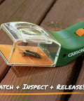 5x Magnifying Bug Catcher With One-Handed Quick Release Trap For Indoor Outdoor Exploration Kids And Adults STEM Learning Toy For Safe Bug Viewing And Easy Release. Green plastic bug catcher on wood with insect inside